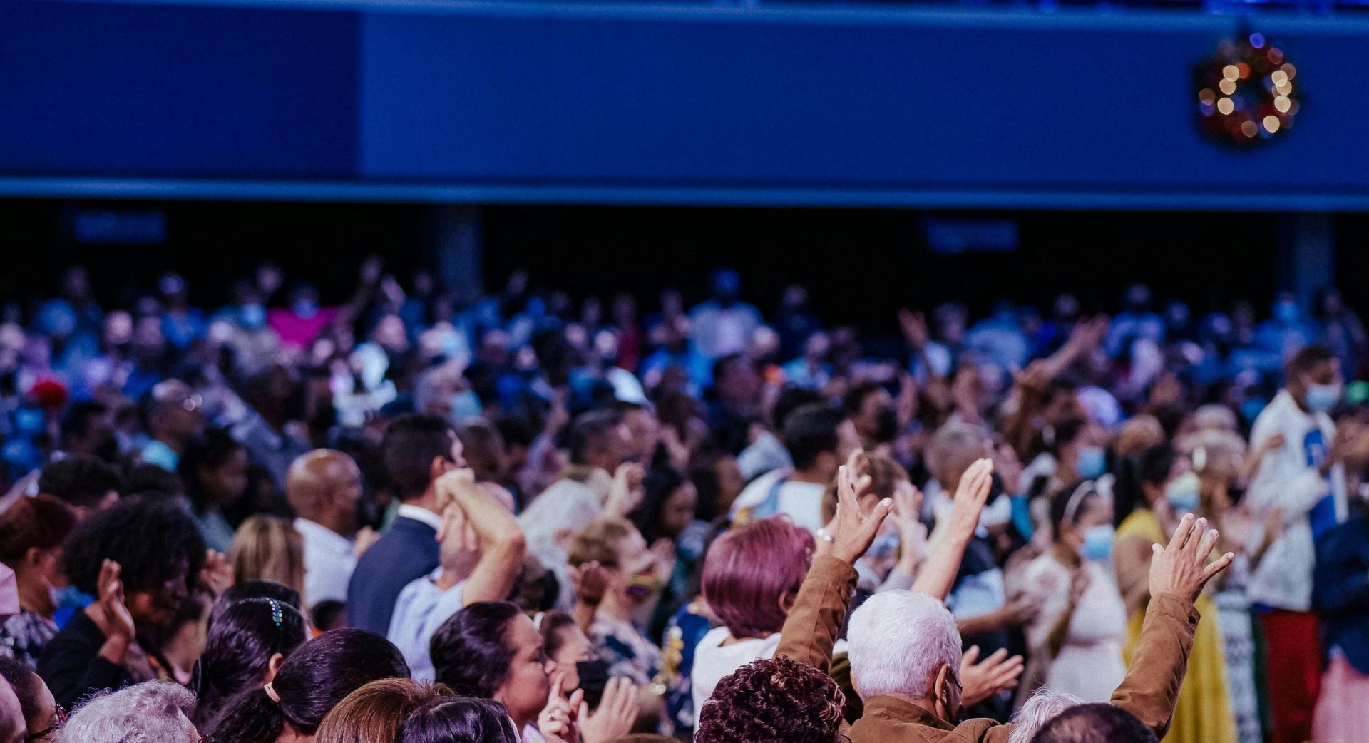 A large congregation engaged in worship inside a vibrant spiritual setting.