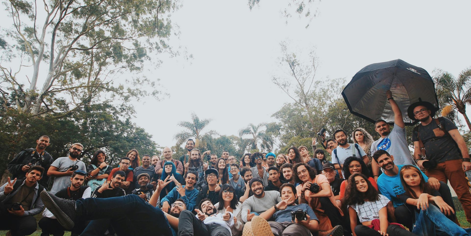 Ground level of multiethnic group of people gathering together near green plants and looking at camera