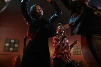 Women enjoying a lively dance indoors, hands raised, wearing trendy outfits.