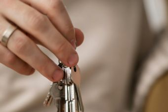 A close-up photograph of hands exchanging keys, symbolizing new home ownership.