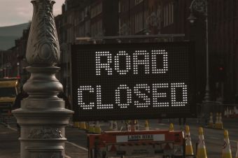 A road closed sign on a city street at dusk, highlighting urban roadwork.