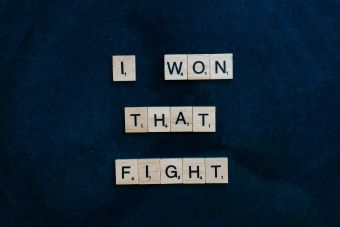 Wooden Scrabble tiles on dark background spelling 'I won that fight.'