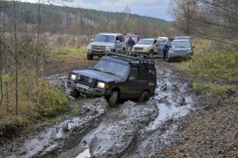 Off-road vehicles navigating a challenging muddy terrain in the countryside forest.