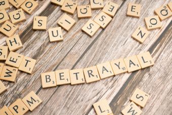 Wooden letter tiles spelling 'Betrayal' on a rustic wooden surface, conveying themes of deceit and dishonesty.