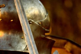 Detailed view of a medieval knight's steel gauntlet grasping a sword, highlighting historical armor.