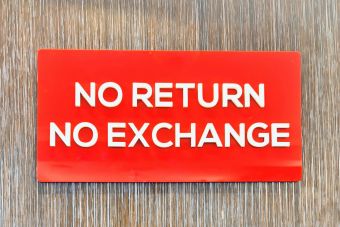 Bold red sign with 'No Return No Exchange' message on a wooden backdrop.