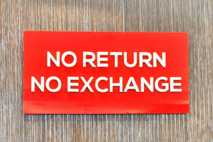 Bold red sign with 'No Return No Exchange' message on a wooden backdrop.