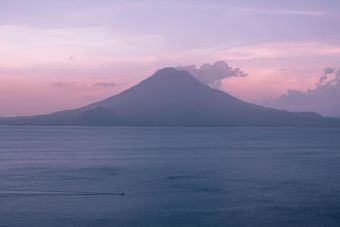 A breathtaking view of a sunset over Lake Atitlán in Guatemala with a volcano silhouette.