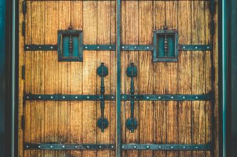 Close-up of vintage wooden doors featuring ornate ironwork and bolts.