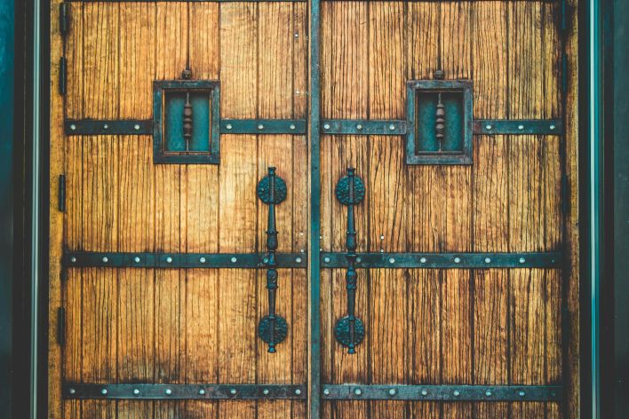 Close-up of vintage wooden doors featuring ornate ironwork and bolts.