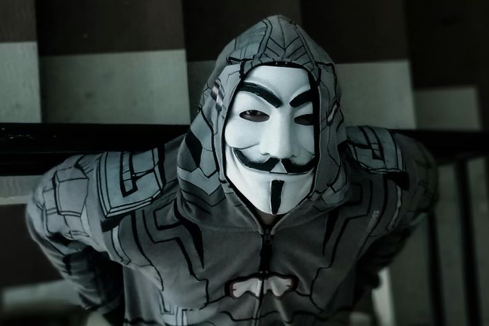 A person wearing a costume mask and hoodie standing on a staircase, creating a mysterious ambiance.