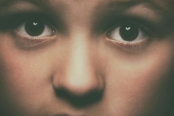 Detailed close-up of a child's face focusing on expressive brown eyes, conveying emotion.