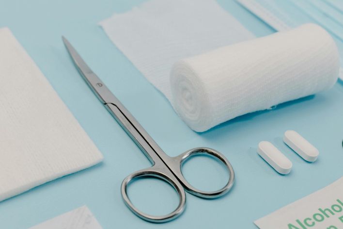 Close-up of medical supplies on a blue background, featuring bandages, pills, and scissors.