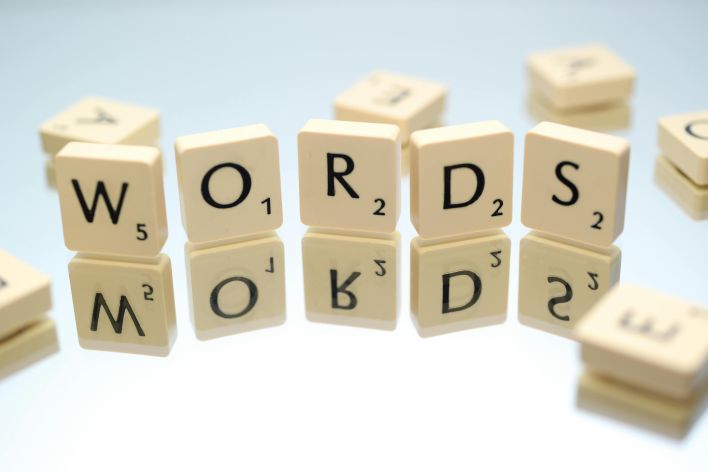 Scrabble tiles spelling 'words' on glass reflecting surface, perfect for language and games themes.