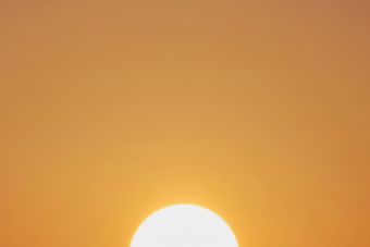 A vibrant sunset with a vivid orange sky and a prominently setting sun.