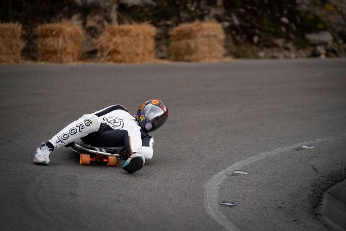 Luge racer in full gear tackling a sharp curve on a downhill track.