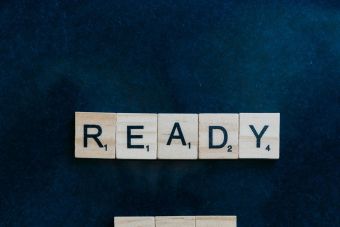 Wooden Scrabble tiles arranged to spell 'Ready for Battle' on a dark background.