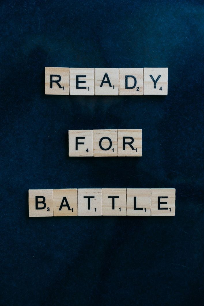 Wooden Scrabble tiles arranged to spell 'Ready for Battle' on a dark background.